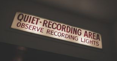 overhead neon sign lit up above recording studio indication a live session is on air