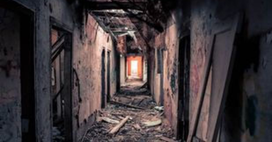 delapidated hallway of abandoned building with glow at the end