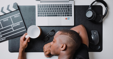 black man asleep at computer desk with coffee