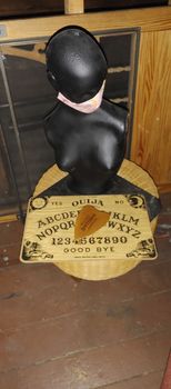 black mannequin torso holding ouija board